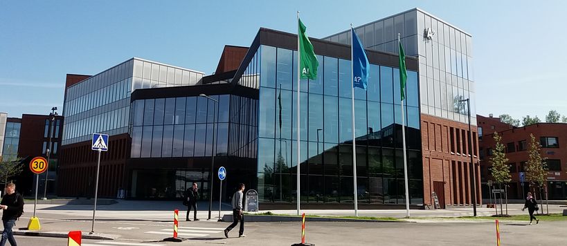 Outside picture of the School of Business building in Otaniemi. Three Aalto Flags swinging in front of the building.