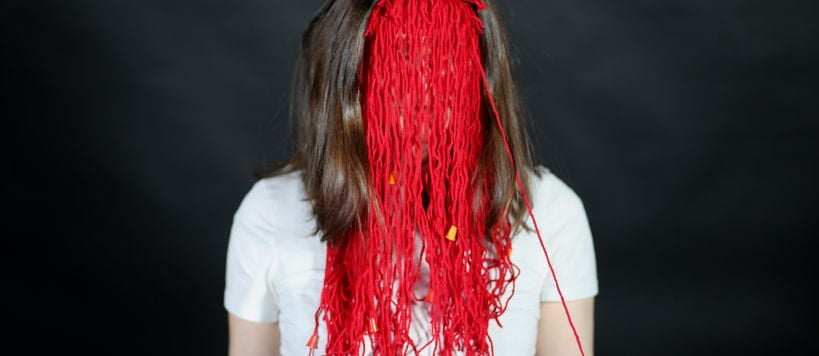 A person behind red mask made of yarn.
