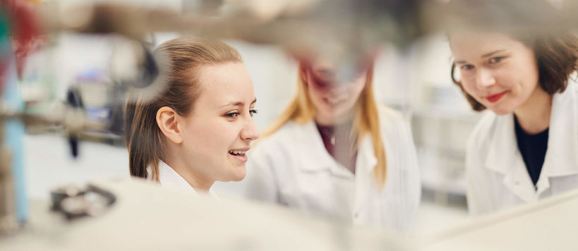 Three researchers in white coats working in laboratory