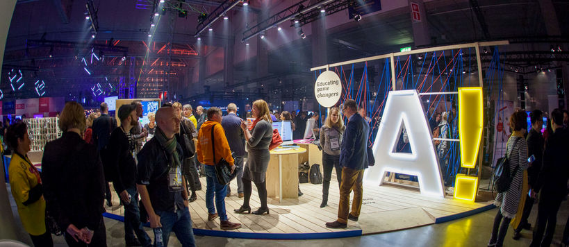 Aalto University's stand at Slush convention with lots of people standing around it