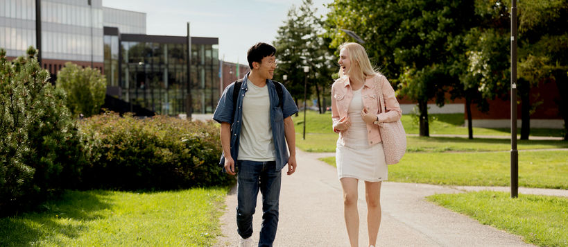 Kaksi opiskelijaa kävelemässä Kauppakorkeakoulun ulkopuolella.