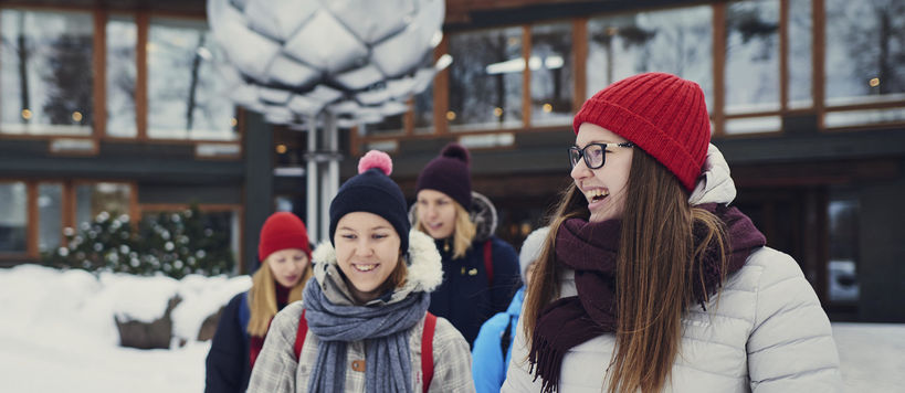 Laughing students in front of Dipoli in the winter, in warm clothing