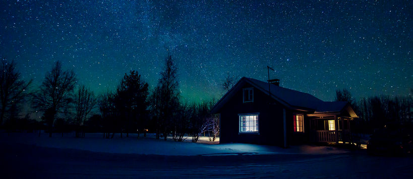 a house in the middle of nowhere in the middle of the night with stars showing in the sky and light coming from the house