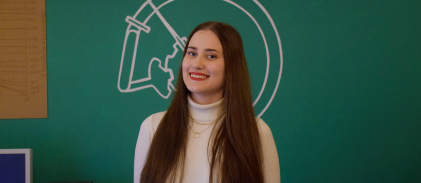 Mariina Tikka hymyilee kameralle, taustalla vihreä seinä.