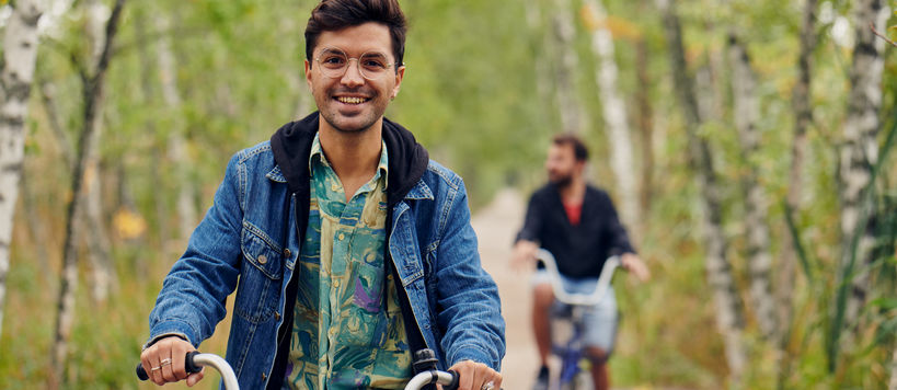 A man smiles on a bike in the nature area outside Otaniemi campus.