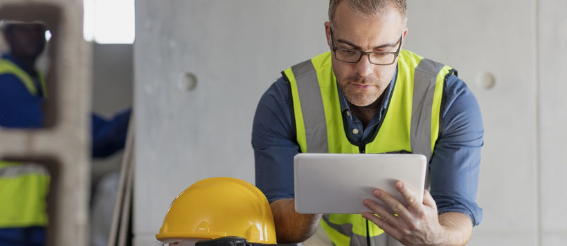 A man uses a tablet computer at a construction site.