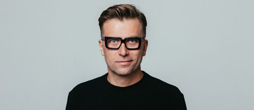 Man with glasses and a black blouse looking at the camera