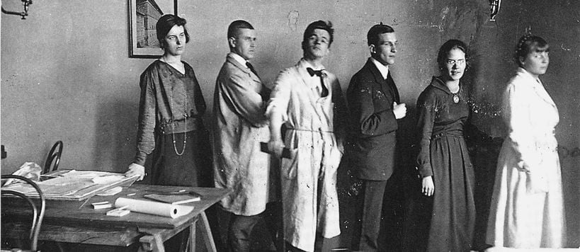 Vuoden 1921 arkkitehtiopiskelijoita poseeraa opetustiloissa jonomuodostelmassa mustavalkoisessa kuvassa
