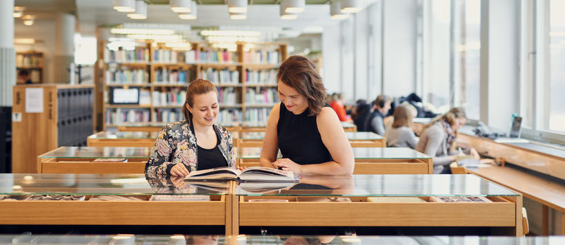 Two women reading together in the Learning Centre library