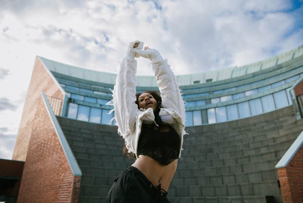 A woman dancing in front of a big university building