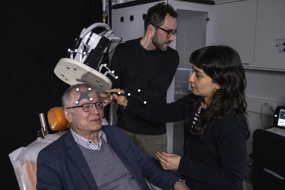Three persons working with a brain imaging device