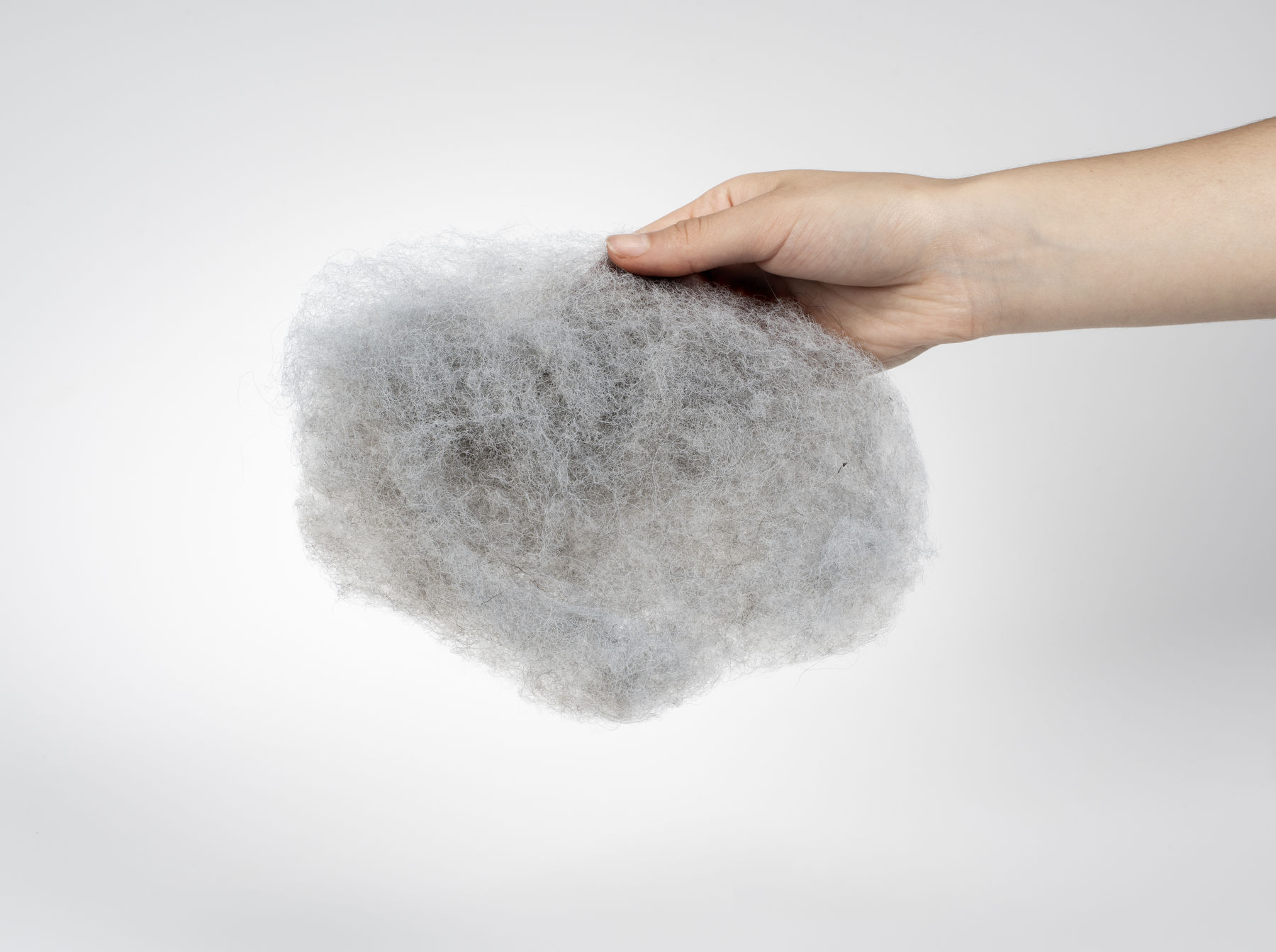 a loose piece of grey coloured wool held by a hand