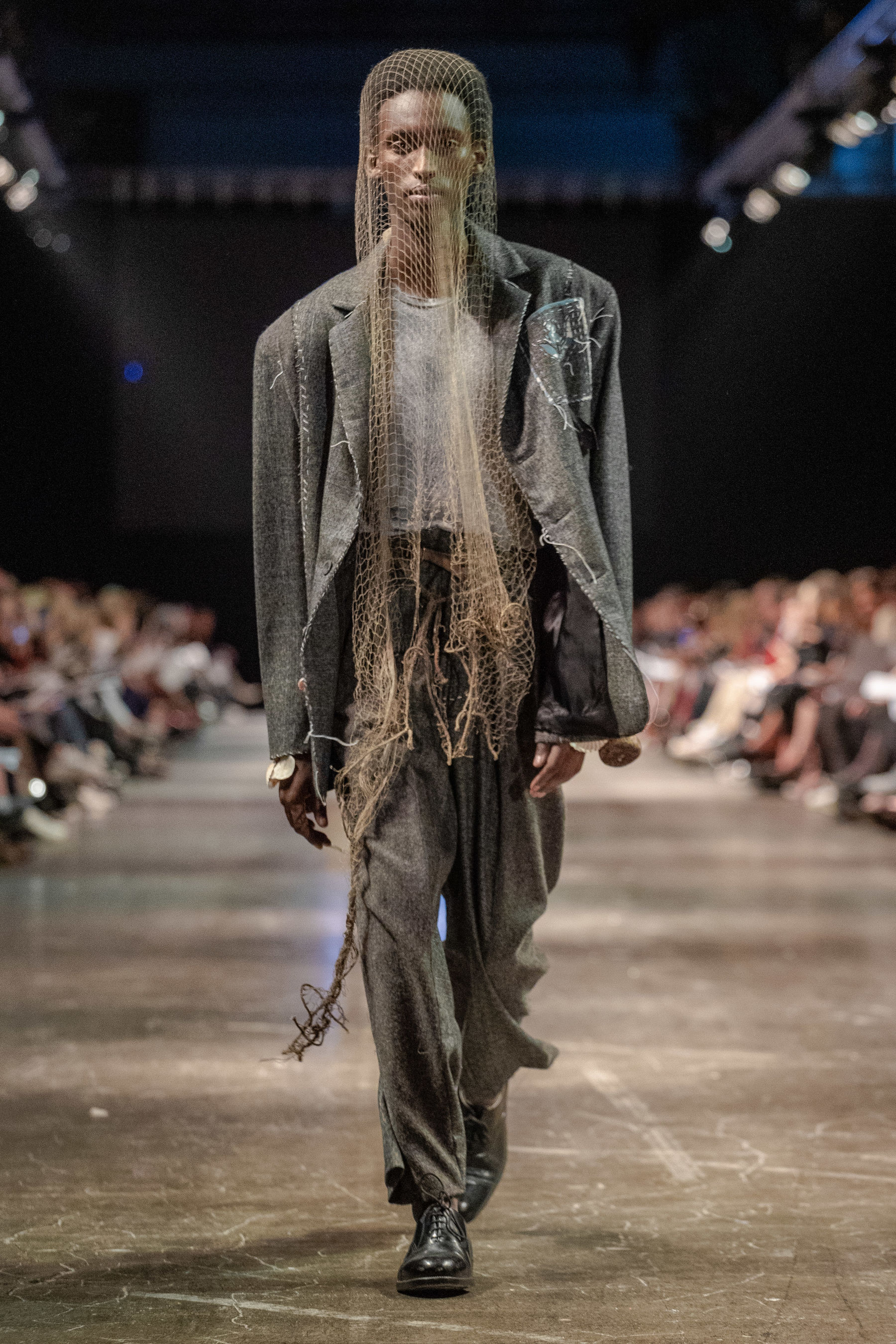 Model walking down catwalk in garment with fishing net