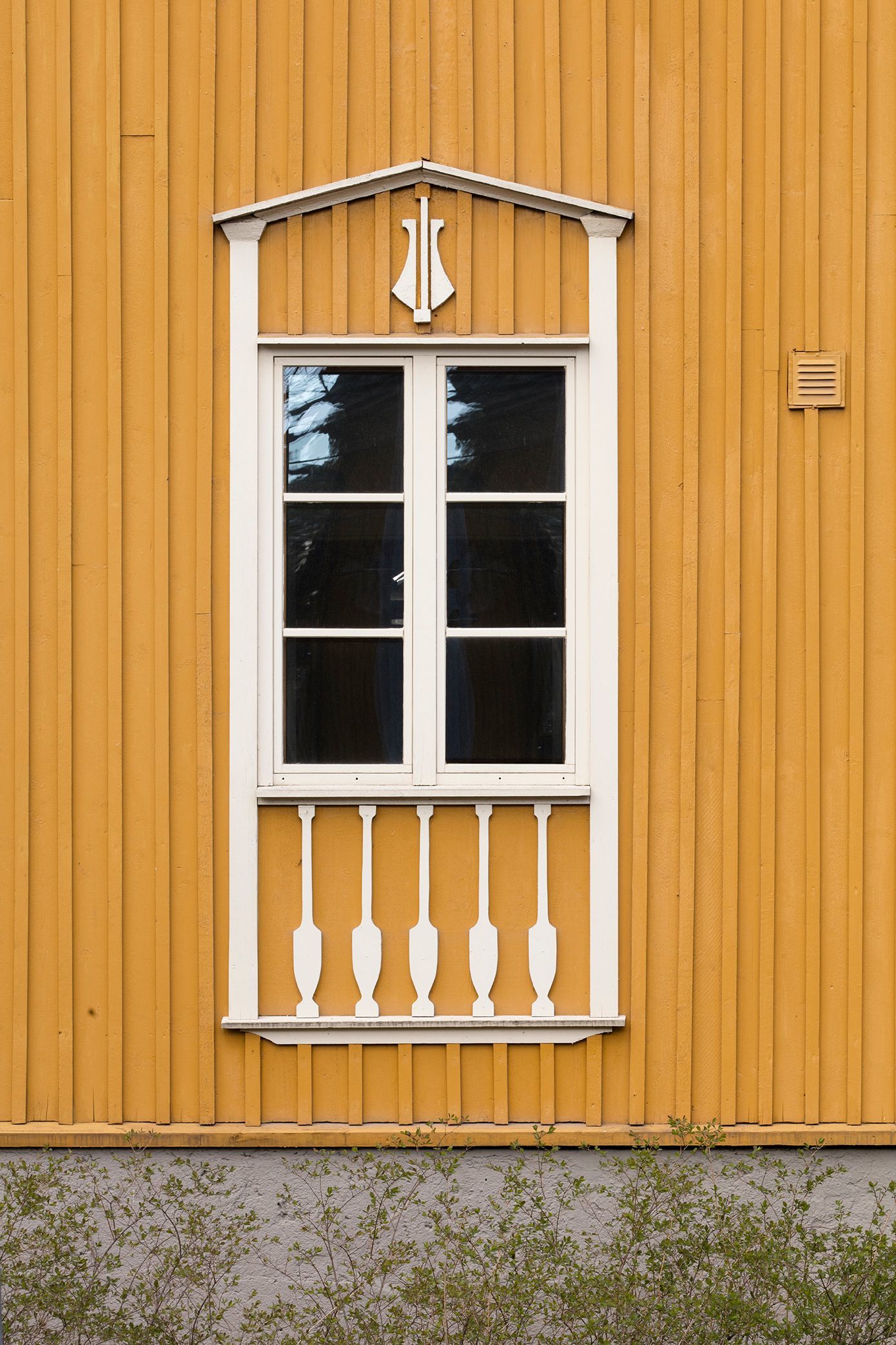 Yksityiskohta keltaisen puutalon ikkunan puitteista ja koristeluista Puu-Käpylässä
