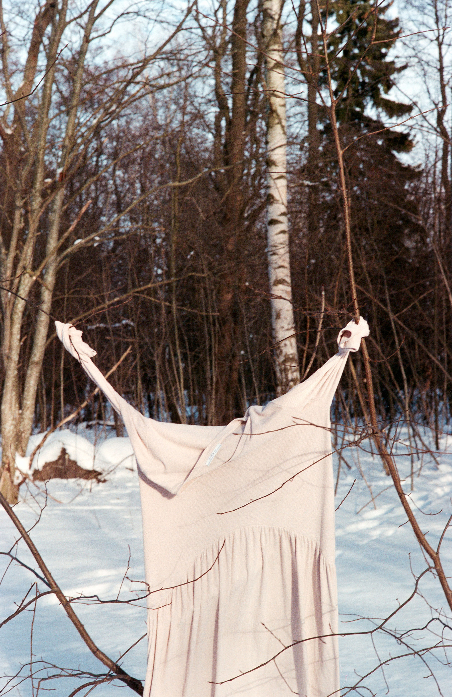 a cream coloured dress hanging from a tree