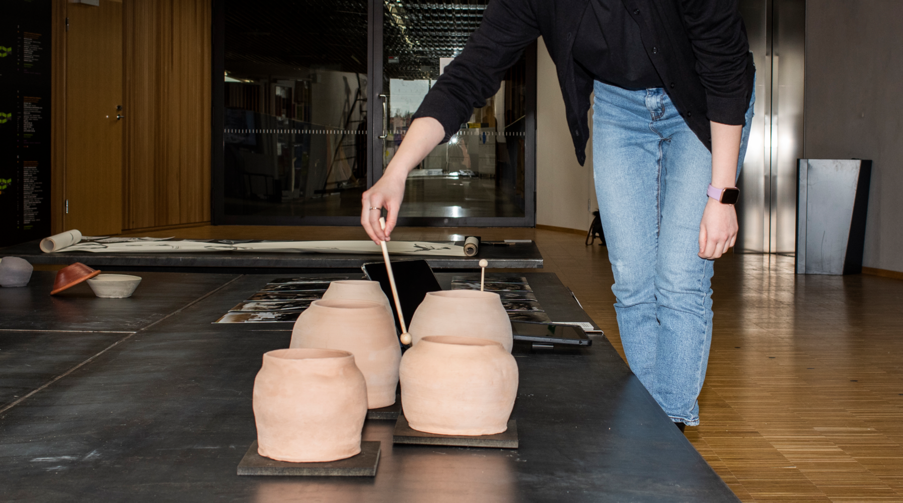 a person standing next to five pots in an exhibition space