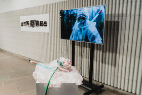 a photo from art exhibition Interspecies liminalities, 2019. A plastic suit, art video (&projector) and an art piece hanging on the wall.
