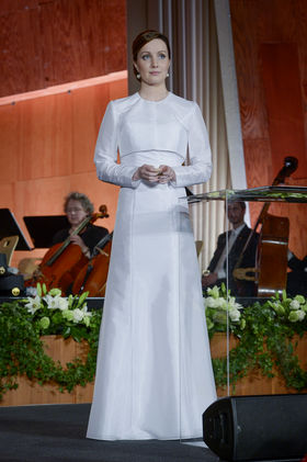 Kuvassa valkoiseen pukeutunut nainen juhlasalin lavalla