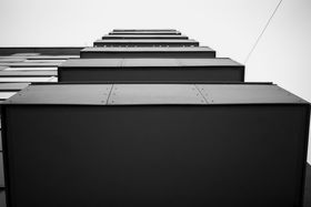 Mustavalkoinen kuva alhaalta päin kuvatusta rakennuksesta ja sen parvekkeista, jotka näyttävät rajauksessa pieneneviltä bokseilta.