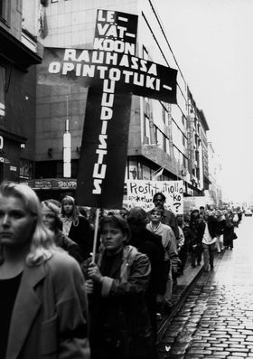  Student Aid Demonstration 1993. Procession along Aleksanterinkatu to the west. Cross-shaped demonstration sign: "Let the student aid reform rest in peace". Photo: TKY Photo Archive, AYY Archive