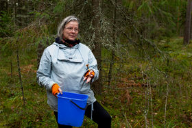 Professor Laura Beloff talks about mushrooms. She holds a blue bucket and a single mushroom.