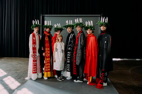 Designer with seven models wearing headpieces with candles