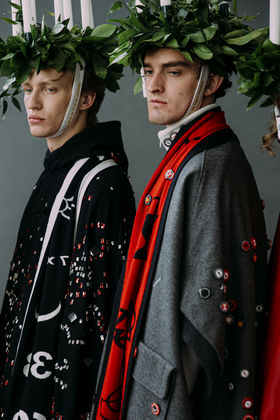 Two men in headpieces with candles and garments in grey, red and black