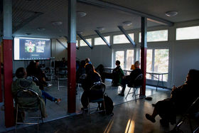 Participants sit, spaced out, in Hietsun Paviljonki, facing a zoom meeting and discussing the project.