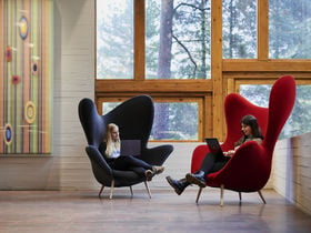 Two students are sitting in large, colourful chairs inside Dipoli