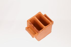 Red clay container that is cubic with a slot in between and two rectangular handles on the sides