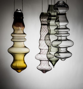 four bubbly-shaped glass pieces hanging with light grey background