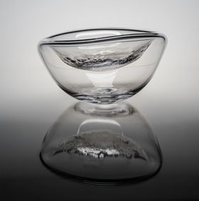 a close-up of a cup-shaped clear glass piece with a reflection underneath