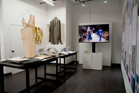 Garment samples hanging from the ceiling, other textile samples on the table on display in the exhibition in New York 