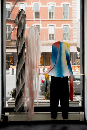 Clothes hanging on display by the window with a streetview in a gallery in New York