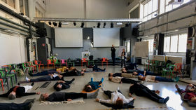 People lying on the floor doing 20 Minute Dance, SPT practice, during CBCR workshop. 