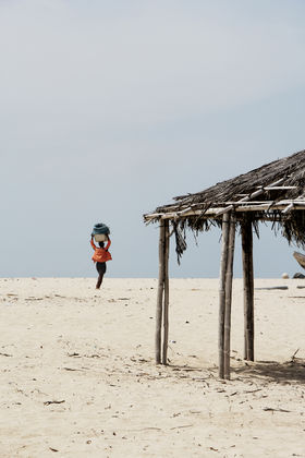 Woman carrying bucket on her head on the beach in Accra