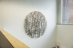 A round artwork made of willow in a white staircase in K1 building.