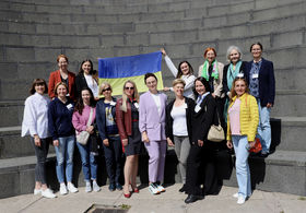 Erasmus+ Staff Training 2023 participants at Aalto University. Ukrainian and finnish colleagues standing  outdoors  with the ukranian flag.