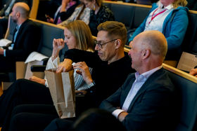 Alexander Stubb reaching inside the gift bag at the AI Revolution seminar at Aalto University on 9 November 2023