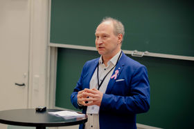 A man in a blue blazer standing and talking