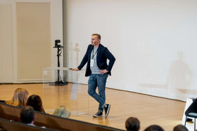 A man in jeans speaking in front of an audience on stage
