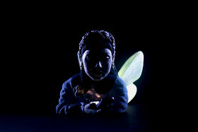 A colourful, ceramic portrait sculpture of a woman with shining butterfly wings, the woman is looking down at her phone