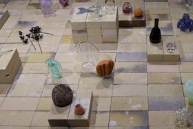 A collection of glass objects exhibited on a layout made of bricks