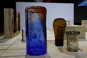 A blue-red cylindrical glass object and some others in the backgrounds