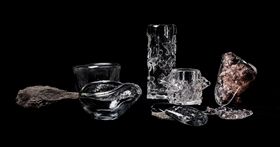 A collection of colourless glass objects and two rocks against a black background