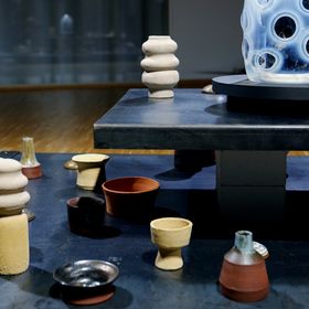 A collection of ceramic objects and a glass sculpture in an exhibition setting