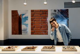 Exhibition display: Three photo prints on the wall depicting various brick surfaces and a collection of clay samples on a table