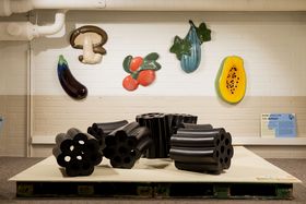A display of large, black ceramic liquorish candies and fruits and vegetables in the back, on the wall