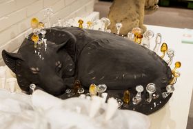 A black ceramic wolf curled up and sleeping, glass mushrooms growing out of it