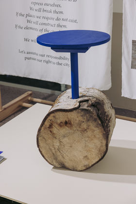 A blue stool like seat attached to a log